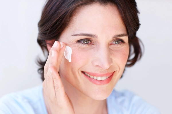 Lächelnde Frau cremt ihre Wangen ein